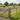 Two people riding horses in an outdoor equestrian arena with a wooden post and rail fence