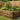 Raised Bed with vegetables growing in it, surrounded by a lawn and encloded with garden fencing