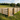 Sawn Post & Rail fence around a sand school with a small 5-bar gate and 3 horses with riders at the far end of the arena.